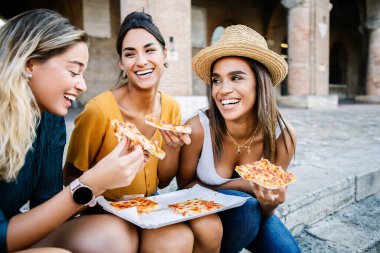 EvotoHappy genç turist bayan arkadaşları İtalya 'da yaz tatili boyunca pizza yerken eğleniyorlar.