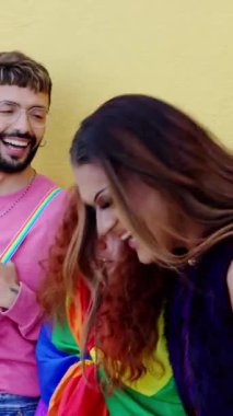 LGBT gay festivali gününü kutlamak için sarı arka plana yaslanan genç insanların dikey videosu. Gay topluluğu kavramı.