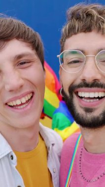 Gay Onur Günü 'nü kutlayan mutlu LGBTQ gençlerinin dikey videosu. Arka planda eğlenen arkadaşlarıyla kameraya gülümseyen homoseksüel erkeklerin portresi. LGBT topluluk kavramı.