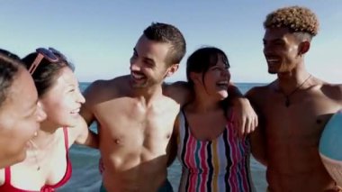 Çeşitli genç arkadaşlar kumsalda eğleniyor. Yaz tatilinin tadını çıkaran gençlerin portresi.