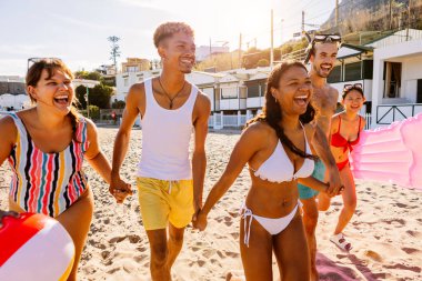 Bir grup mutlu arkadaş sahilde yaz tatilinin tadını çıkarıyorlar..