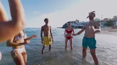 Genç bir arkadaş grubu yaz tatilinde plaj topuyla oynarken eğleniyor.