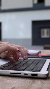 Kampüs kolejinin dışındaki bankta oturan kız öğrencilerin dizüstü bilgisayarda daktilo yazışlarını dikey yakın çekim videosu. Eğitim ve teknoloji kavramı.