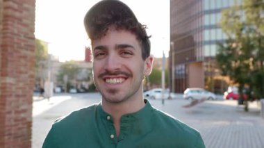 Şehrin caddesinde duran mutlu genç adamın portresi. Neşeli genç üniversite öğrencisi kameraya bakıyor.. 