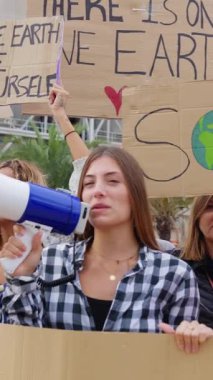 İklim değişikliğini protesto eden pankartlı ve posterli çeşitli insanların dikey HD videosu.