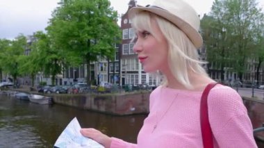 Amsterdam 'ı gezen çekici genç bir bayan turist. Hollanda 'da tatilin tadını çıkaran yaz şapkalı genç bir kadın. Seyahat ve tatil yaşam tarzı kavramı.