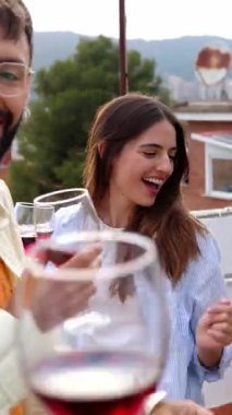 Teras evinde kırmızı şarap içip eğlenen genç arkadaşların dikey HD videosu. Mutlu insanlar doğum günü verandasında birlikte eğleniyorlar. Arkadaşlık yaşam tarzı konsepti.