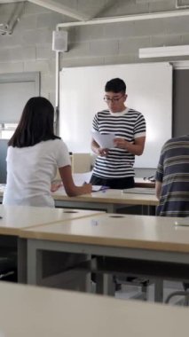 Dikey video. Latin Amerikalı öğrenci sınıftaki çok uluslu sınıf arkadaşlarına projeyi açıklıyor. Perulu genç çocuk lisede bireysel bir sunum yapıyor. Eğitim kavramı.