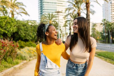Şehir caddesinde yürürken eğlenen iki genç kadın. Arkadaşlık ve gençlik toplumu kavramı.