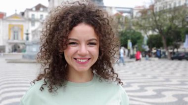 Genç gülümseyen Faslı kız şehir caddesinde kameraya bakıyor. Lizbon, Portekiz 'de tatilin tadını çıkaran neşeli bayan turist.