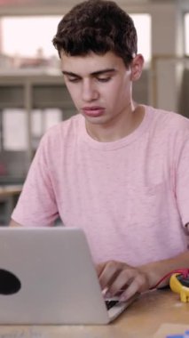 Lisedeki teknoloji dersi sırasında dizüstü bilgisayarda çalışan genç bir çocuk. Eğitim yaşam tarzı kavramı.