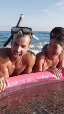 Şişme minderli bir arkadaş grubu yazın denizde eğleniyor. Tatil yaşam tarzı ve arkadaşlık kavramı.