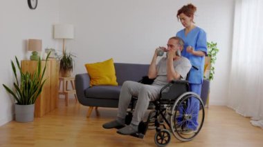 Evde dambıl kullanarak fizyoterapist eğitimi alan yaşlı bir adam. Kadın terapist, huzurevi hizmetlerinde kıdemli adama yardımcı oluyor..