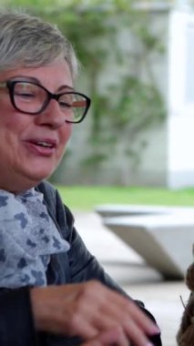 Emekli insanların Kafe Bar 'da kahvaltı edişinin dikey videosu. Olgun arkadaşlar kafeterya terasında cappuccino içerek boş zamanın tadını çıkarıyorlar. Yiyecek ve içecek konsepti.