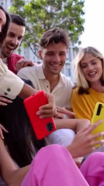 Dışarıda cep telefonuyla eğlenen genç nesil Z 'lerin dikey HD videosu. Akıllı telefon uygulamasında sosyal medyadan keyif alan neşeli öğrenci topluluğu.