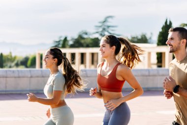 Üç genç atletik arkadaş yazın dışarıda birlikte koşuyorlar. Sağlıklı yaşam tarzı ve spor anlayışı