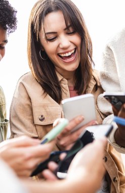 Dikey fotoğraf. Dışarıda cep telefonu kullanan genç bir grup insan. Sayısal ağ uygulamasında sosyal medya içeriğini paylaşan binlerce yıllık çeşitli arkadaşlar. Teknoloji konsepti