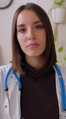 Tıbbi konsültasyonda dizüstü bilgisayarında video görüntüsü olan kadın doktorların dikey görüntüsü. Genç bir sağlık çalışanı hastanenin işyerindeki internet görüşmesinde hastayla konuşuyor. Teletıp kavramı.
