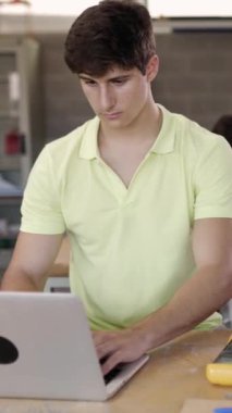 Teknoloji sınıfında dizüstü bilgisayarla çalışan genç bir öğrencinin dikey HD videosu. Eğitim kavramı.