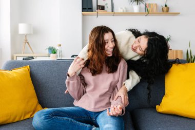 Genç bayan arkadaşlar evde birbirlerine sarılırken eğleniyorlar. Genç kızlar birlikte vakit geçiriyorlar. Arkadaşlık kavramı.