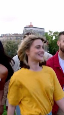 Dikey video. Bir grup genç arkadaş dışarıda eğleniyor. Milenyum gençleri şehir parkında eğleniyor. Arkadaşlık ve toplum kavramı.