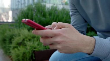 Şehir caddesinde cep telefonu kullanan genç adam ellerini kapat. Milenyum Kafkas 'lı adam şehir geçmişi hakkında akıllı telefondan konuşuyor..