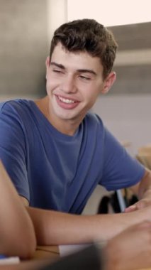 Lise öğrencisinin sınıf arkadaşıyla aynı masada oturup ders çalışmasının dikey videosu. Gençler okulda grup egzersizi yapıyor. Eğitim ve takım çalışması kavramı.