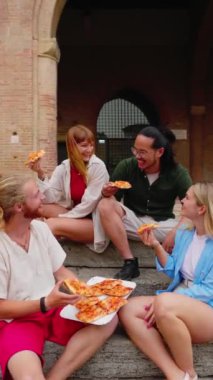 İtalya 'da yaz tatilinin tadını çıkarırken birlikte pizza yiyen bir grup mutlu arkadaşın dikey HD videosu. Dört milenyum insanı dışarıda eğleniyor.. 