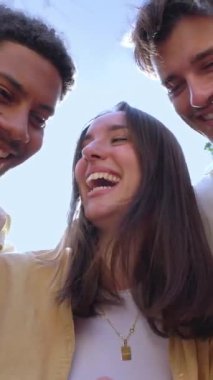 Genç bir grup insan dışarıda cep telefonuyla eğleniyor. Akıllı telefon uygulamasında sosyal medyadan keyif alan neşeli öğrenci topluluğu. Dikey HD video.