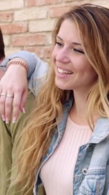 Dikey video. Mutlu, genç, çok ırklı öğrenci arkadaşlar birlikte gülüp eğleniyorlar. Gençlik toplumu konsepti. Bin yıllık erkek ve kadınların birbirlerine sarılmaları. Şehir sokaklarında birlik göstermeleri..