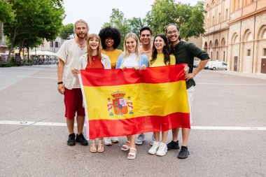 Dışarıda İspanyol bayrağı tutarken kameraya gülümseyen çeşitli gençlerden oluşan bir grup. Farklı milletlerden gelen uluslararası toplum birlik gösteriyor