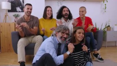 Evde karaoke yaparak eğlenen çok nesilli bir ailenin yakın görüntüsü. Dedem ve torunum mikrofonlarıyla birlikte şarkı söylüyorlar. Boş oyun konsepti.
