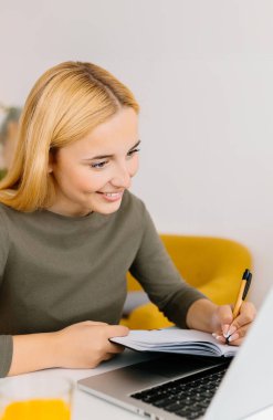Evde dizüstü bilgisayar kullanan genç bir kızın dikey görüntüsü. Milenyum Avrupalı kadın çevrimiçi sanal video dinlemeyi öğreniyor. İş ve eğitim kavramı.