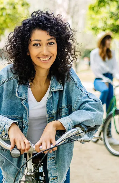 Kiralık bisikleti olan güzel bir kızın dikey portresi açık havada kameraya gülümsüyor. Bayan arkadaşlar dışarıda birlikte yaz tatilinin tadını çıkarıyorlar. Seyahat ve insan konsepti.