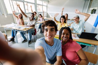 Sınıfta konferans sırasında selfie çeken bir grup mutlu lise öğrencisi. Çeşitli bin yıllık sınıf arkadaşları eğleniyor. Okula, gençlik cemiyetine ve eğitim konseptine dönüş.
