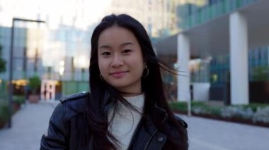 Üniversite kampüsünde kameraya gülümseyen Asyalı genç kız portresi. Eğitim ve gençlik kavramı.