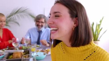 Mutlu genç bir kadın, ailesiyle akşam yemeği partisinden zevk alıyor. Masada oturmuş beyaz şarap içen güzel bir kadının yan görünümü.