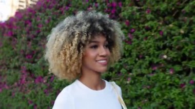 Şehir caddesinde yürüyen genç ve güzel Latin Amerikalı kadının yakın görüntüsü. Neşeli milenyum melez kadınlar yazın açık havada yürüyüş yapıyorlar. İnsanlar ve mutluluk kavramı.