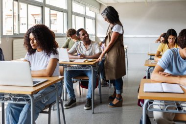 Lise son sınıf bayan öğretmeni, lise öğrencisinin sınıfta egzersiz yapmasına yardım ediyor. Eğitim ve kolej insanları kavramı