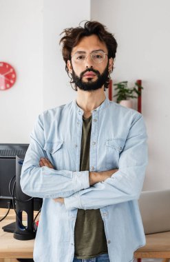 Modern iş yerinde duran genç ve yaratıcı bir adamın dikey portresi. Stüdyo ofisindeki serbest çalışan erkek portresi. Girişimci ve küçük işletme kavramı.