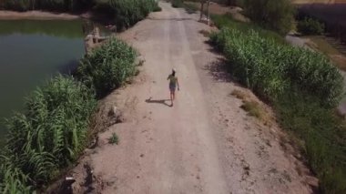 Kırsal kesimdeki bir bataklığa yakın yürüyen genç bir kadının hava manzarası.
