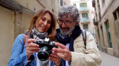 Yaz tatili boyunca kameralarında fotoğraflarına bakan evli turist çifti. Yaşlılar ve seyahat kavramı.