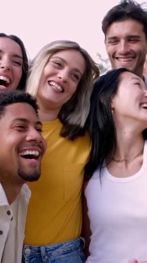 Dışarıda eğlenen bir grup öğrencinin dikey videosu. Çok ırklı genç arkadaşlar gülerek boş günlerin tadını çıkarıyorlar. Gençlik toplumu ve arkadaşlık kavramı.