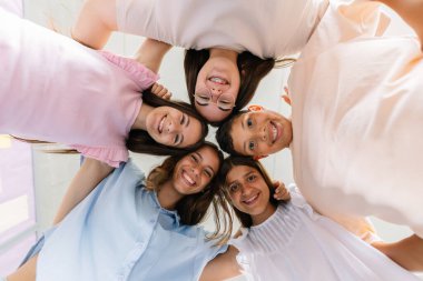 İlköğretim sınıfında çember oluşturan gülümseyen okul çocuklarının düşük açılı portresi. Çocuk eğitimi ve arkadaşlık kavramı.