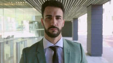 Kameraya doğru yürüyen yakışıklı iş adamının kendinden emin portresi. Başarılı gülümseyen, takım elbiseli yetişkin bir adam kameraya bakıyor. İş ve insan kavramı