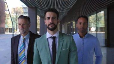 Üç iş arkadaşı güvenli bir şekilde ofis koridorunun dışında kameraya doğru gülümsüyor.. 