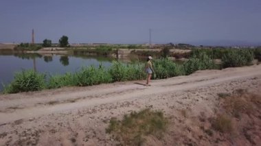 Güneşli bir günde kırsalda bir bataklığa yakın yürüyen genç bir kadının hava manzarası.. 