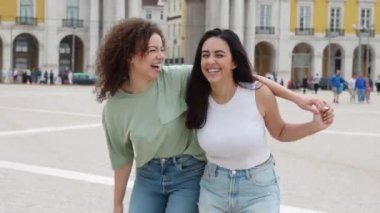 Şehir caddesinde eğlenirken birlikte yürüyen genç ve mutlu kadınlar. Milenyum bayan arkadaşları Lizbon 'da yaz tatilinin tadını çıkarıyorlar. Arkadaşlık, tatiller ve seyahat yaşam tarzı konsepti.