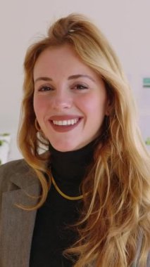 Ofiste kameraya bakan genç ve güzel bir iş kadınının dikey HD video portresi. Bin yıllık profesyonel kadın işçinin gülümsemesi ön planda. İş adamları konsepti.