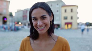 Şehir caddesinde kameraya gülümseyen beyaz güzel bir kadının yakın plan portresi. Mutluluk ve pozitif insanlar kavramı.